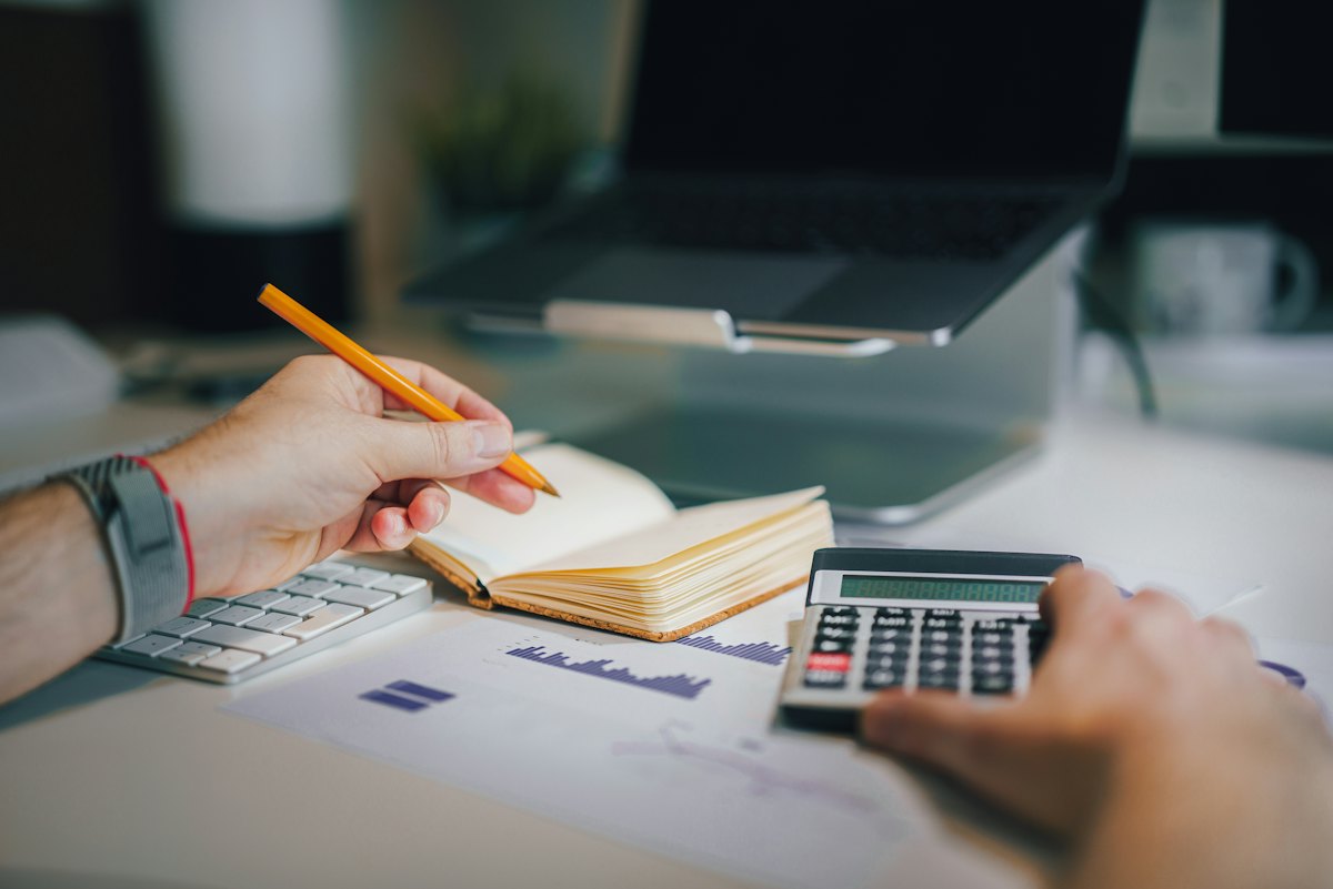 Mesa de trabalho com caderno, calculadora e anotações de planejamento